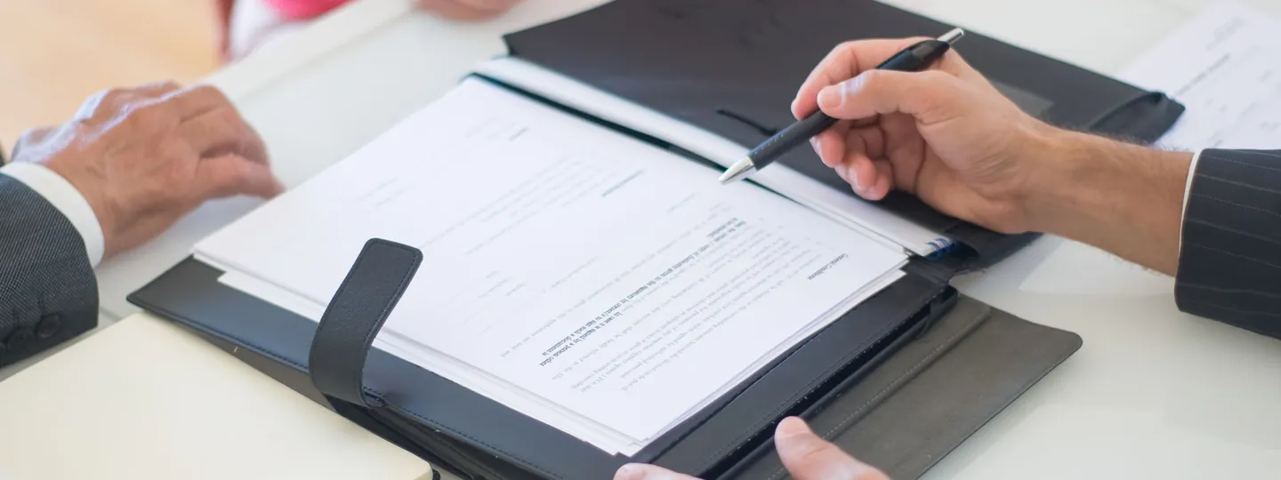 Revisión y firma de documentos en una reunión de asesoría